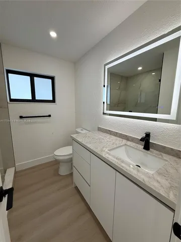 a bathroom with a granite countertop toilet sink and mirror