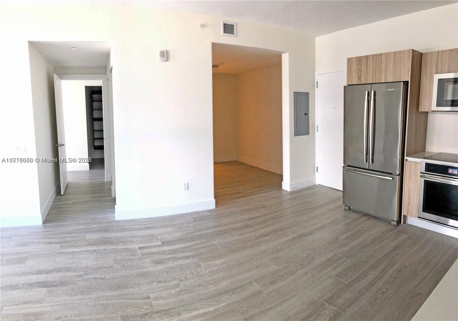 2960 Northeast 207th Street, Unit 1006 Aventura, FL 33180 - Photo 7 of 9 a view of a kitchen with wooden floor and a refrigerator