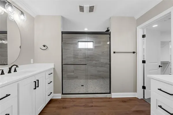 a spacious bathroom with a double vanity sink a mirror and a shower