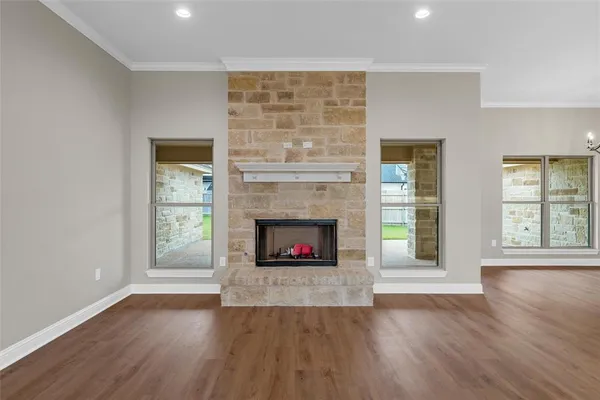 an empty room with wooden floor fireplace and windows