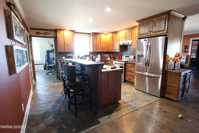 a kitchen with granite countertop a refrigerator a stove a sink dishwasher a dining table and chairs with wooden floor