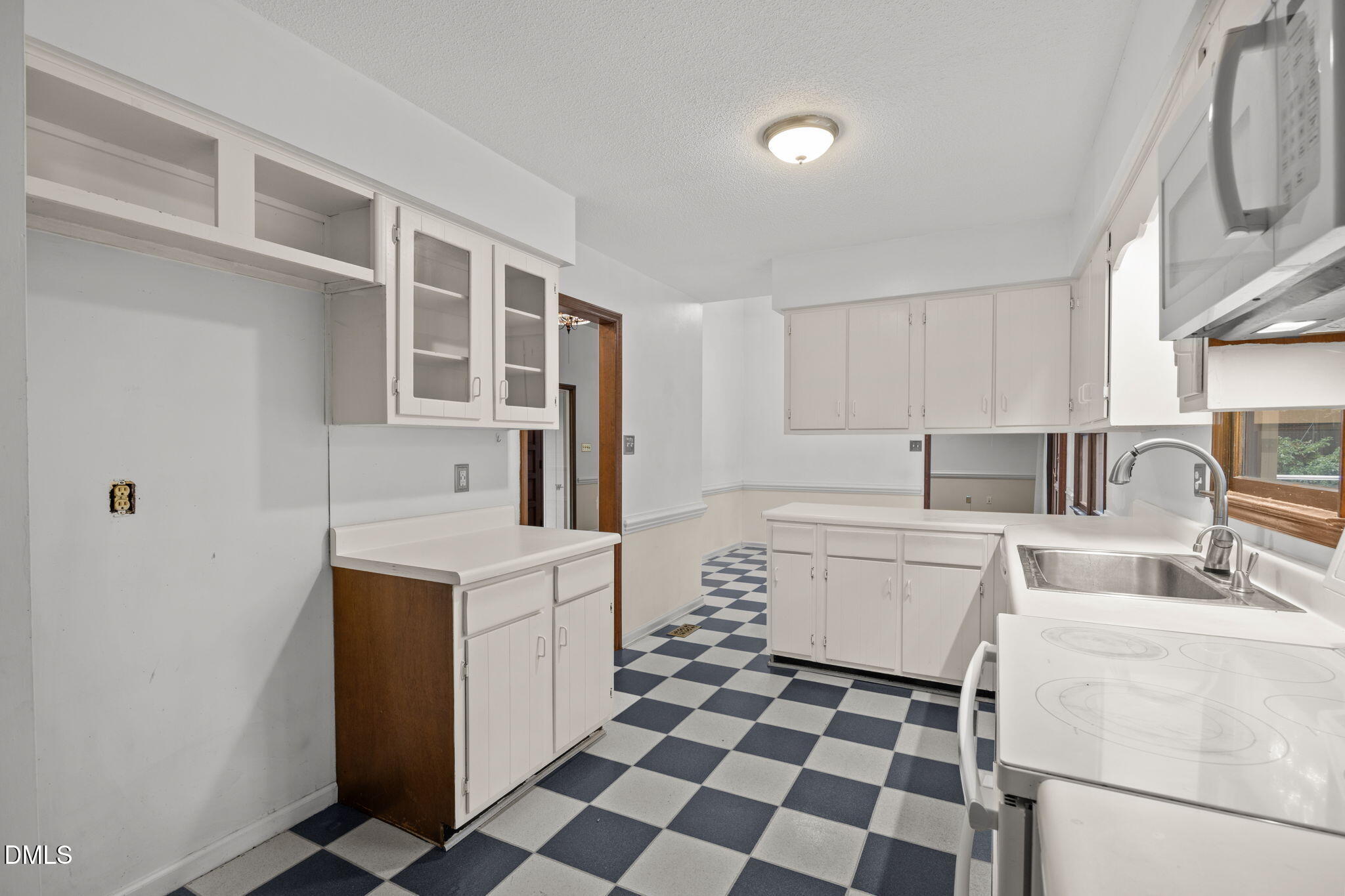 2713 Salisbury Plain Raleigh, NC 27613 - Photo 17 of 39 a kitchen with a checkered floor and white cabinets