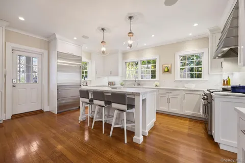 a kitchen with stainless steel appliances kitchen island granite countertop a table chairs sink and cabinets