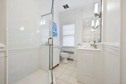 a bathroom with a granite countertop sink a toilet a mirror and shower