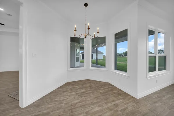 a view of an empty room with windows and ceiling fan