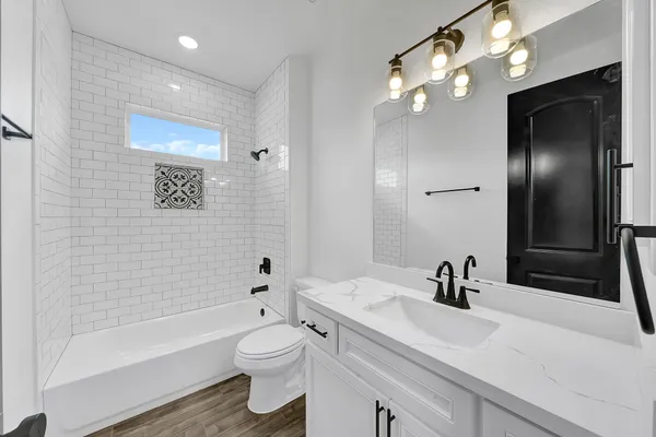 a bathroom with a toilet a sink a tub and a mirror