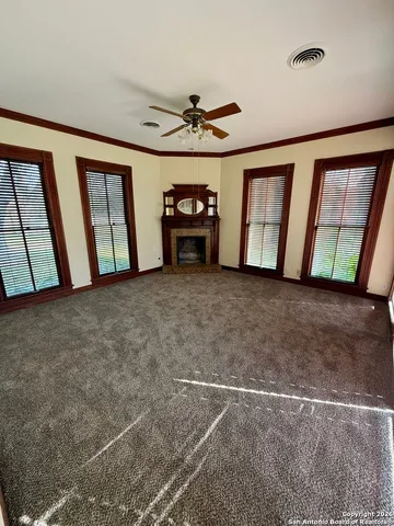 a view of an empty room with chandelier fan and windows