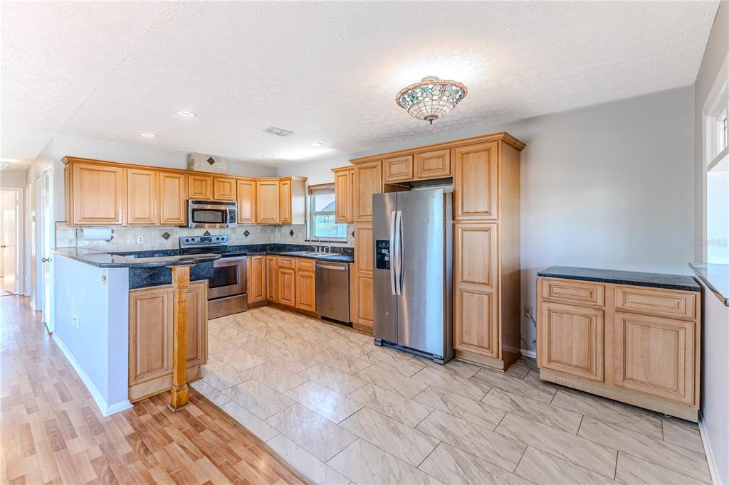 3397 Crape Myrtle Drive Hernando Beach, FL 34607 - Photo 38 of 76 a kitchen with stainless steel appliances granite countertop a refrigerator a stove a sink a washer dryer and white cabinets