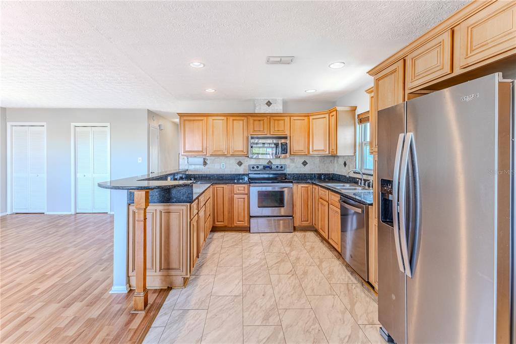 3397 Crape Myrtle Drive Hernando Beach, FL 34607 - Photo 39 of 76 a kitchen with stainless steel appliances granite countertop a refrigerator a sink dishwasher a stove with wooden cabinets and floor