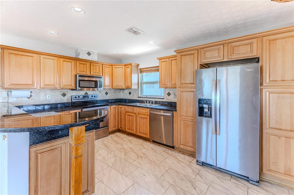 3397 Crape Myrtle Drive Hernando Beach, FL 34607 - Photo 40 of 76 a kitchen with stainless steel appliances granite countertop a refrigerator and a stove top oven