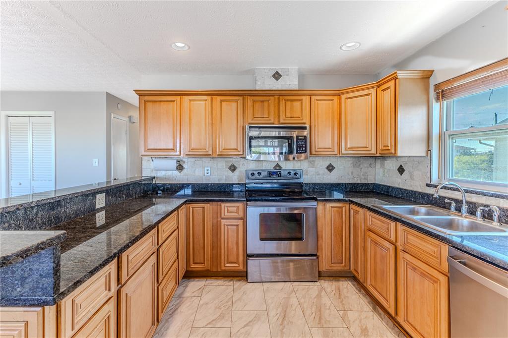 3397 Crape Myrtle Drive Hernando Beach, FL 34607 - Photo 41 of 76 a kitchen with stainless steel appliances granite countertop a sink stove and cabinets