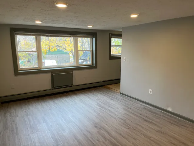 an empty room with wooden floor and windows