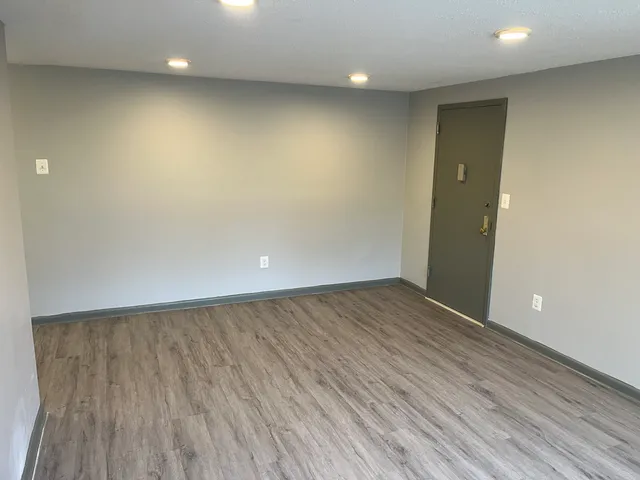 an empty room with wooden floor and entrance