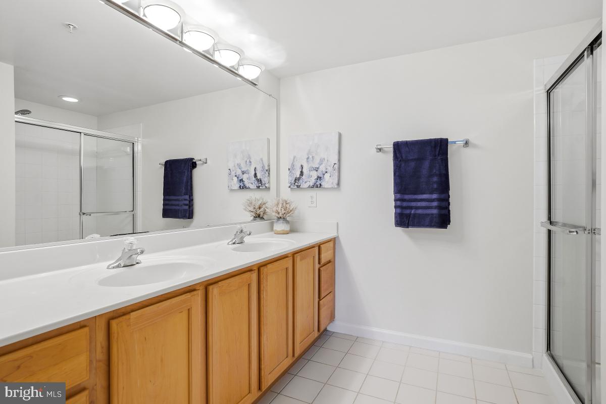 7915 Eastern Avenue Northwest, Unit 1208 Silver Spring, MD 20910 - Photo 20 of 33 a bathroom with a double vanity sink a mirror and a shower
