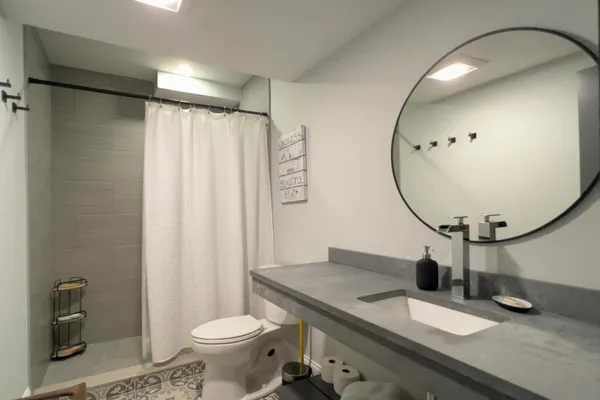 a bathroom with a granite countertop toilet sink mirror and vanity