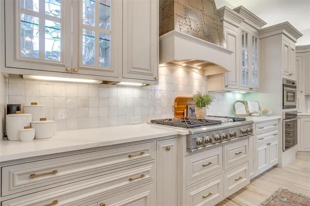 a kitchen with stainless steel appliances granite countertop white cabinets and a window