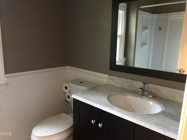 a bathroom with a granite countertop toilet sink and mirror