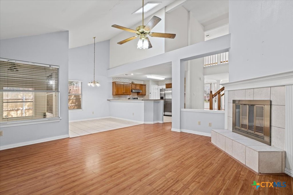 12502 Fallen Tower Lane Austin, TX 78753 - Photo 11 of 28 a large white kitchen with kitchen island a stove a sink dishwasher and a fireplace with wooden floor
