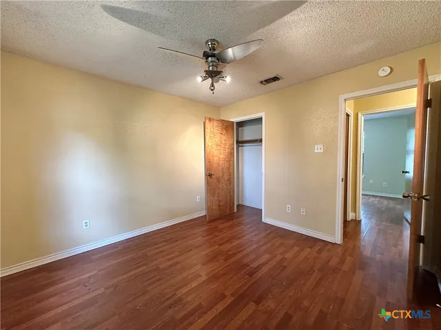 an empty room with wooden floor and fan