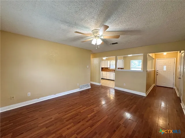 an empty room with wooden floor and windows
