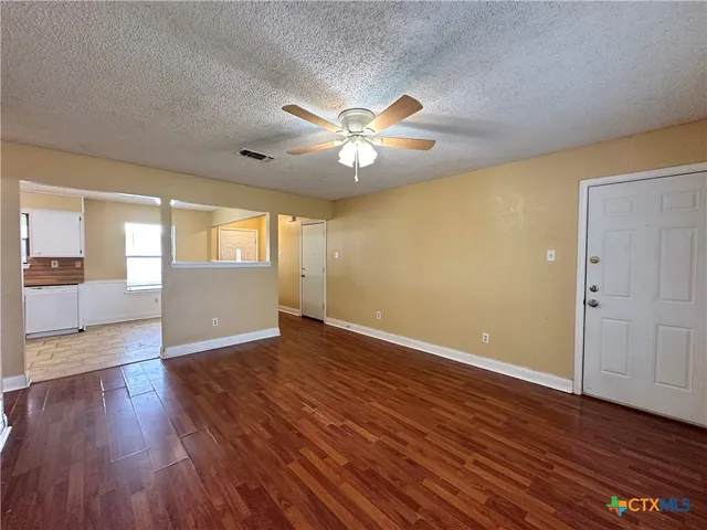 a view of an empty room with window and wooden floor