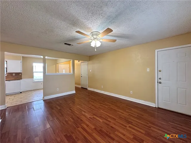 a view of an empty room with window and wooden floor