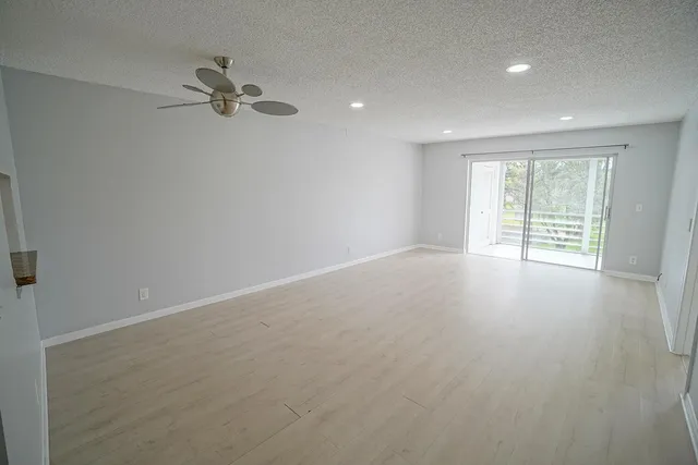 an empty room with windows and fan