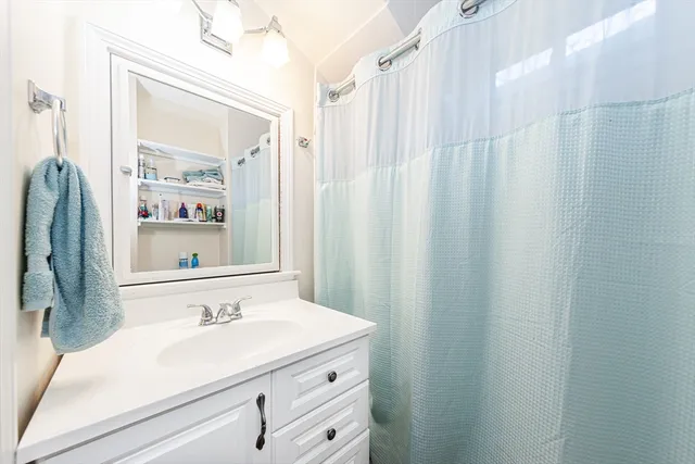 a bathroom with a sink a mirror and a shower curtain