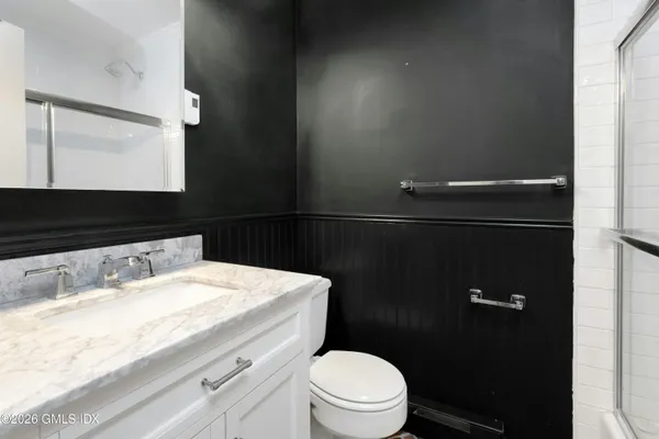 a bathroom with a granite countertop sink toilet and mirror