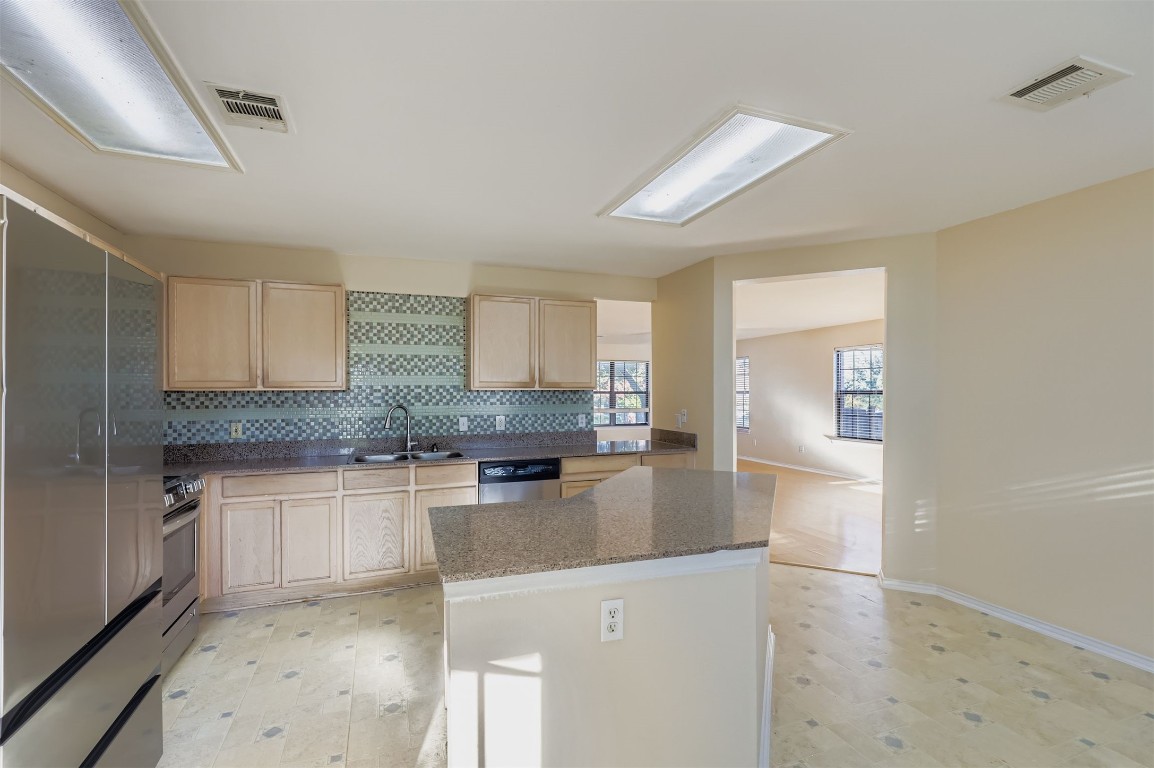 1105 American Robin Path Pflugerville, TX 78660 - Photo 9 of 32 a kitchen with stainless steel appliances granite countertop a sink stove and refrigerator