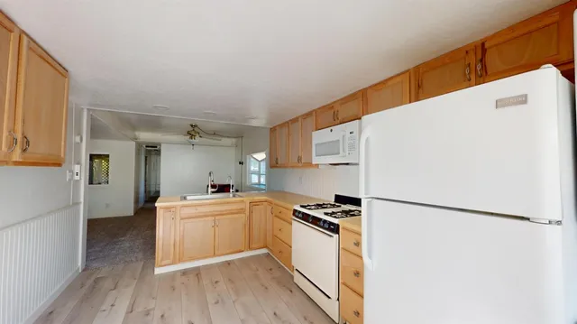 a kitchen with a refrigerator a stove top oven and a wooden floor