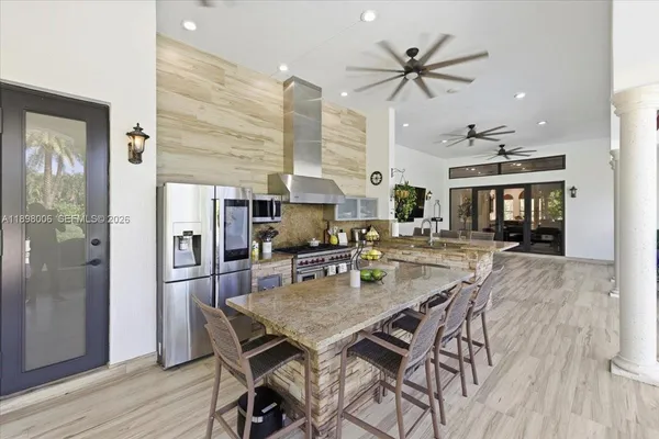 a kitchen with stainless steel appliances granite countertop a stove top oven a sink dishwasher a dining table and chairs with wooden cabinets