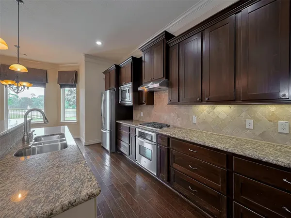 a kitchen with stainless steel appliances granite countertop wooden cabinets a stove top oven and granite counter tops