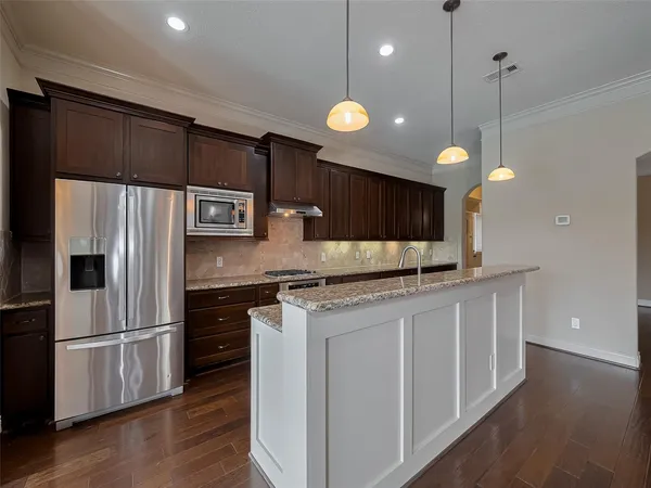 a kitchen with stainless steel appliances a sink a stove a refrigerator and island with wooden floor