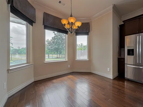 a view of an empty room with window and wooden floor