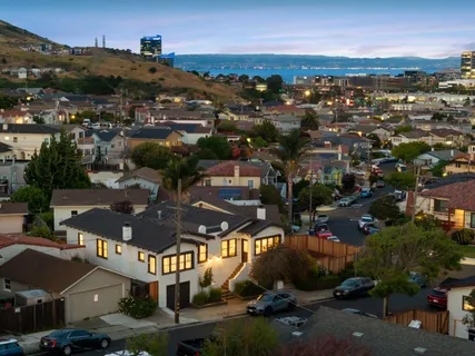 an aerial view of a city with lots of residential buildings and mountain view in back