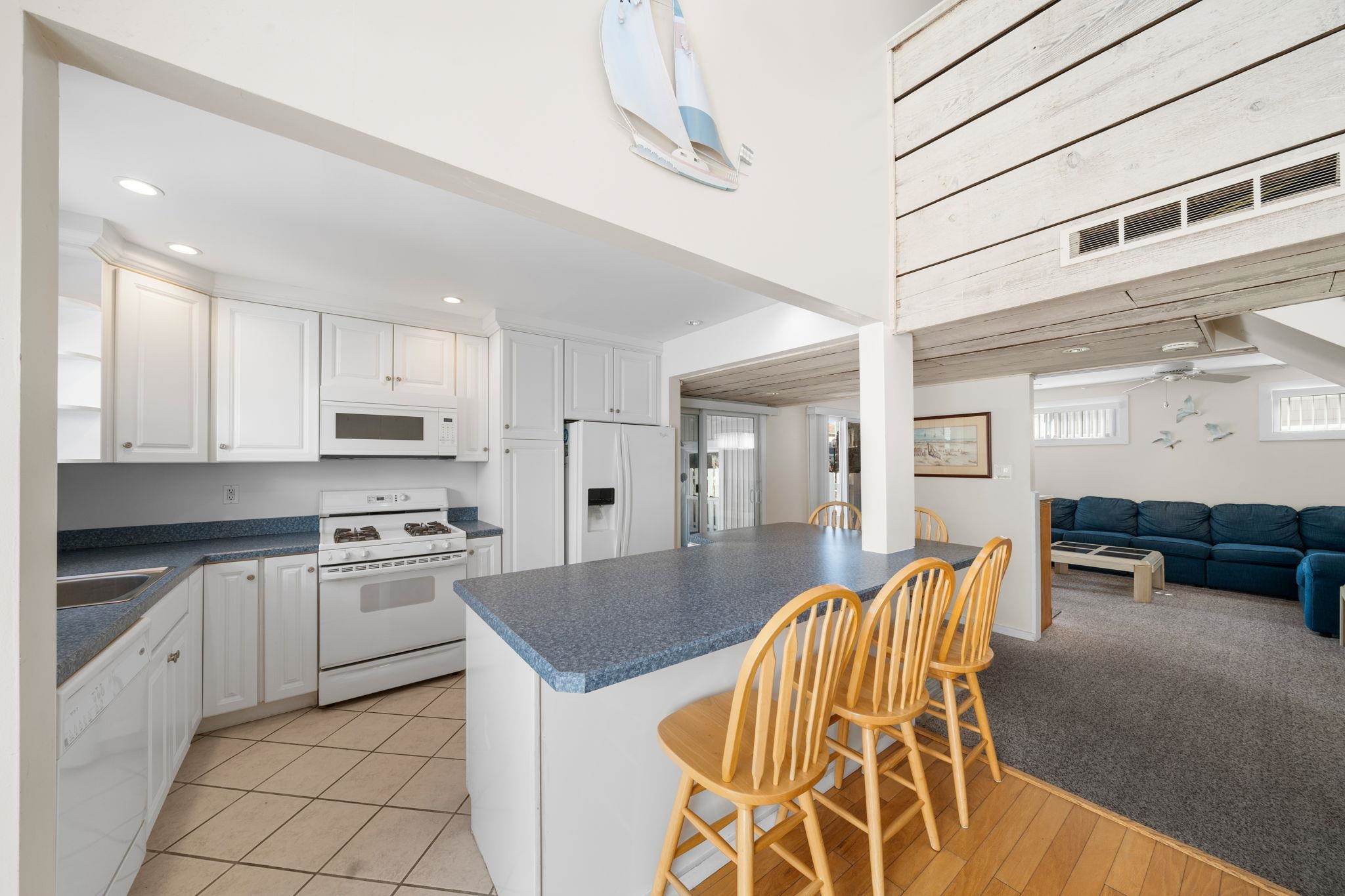 45 19th Street Avalon, NJ 08202 - Photo 8 of 50 a kitchen with stainless steel appliances granite countertop a stove top oven a sink a dining table and chairs with white cabinets