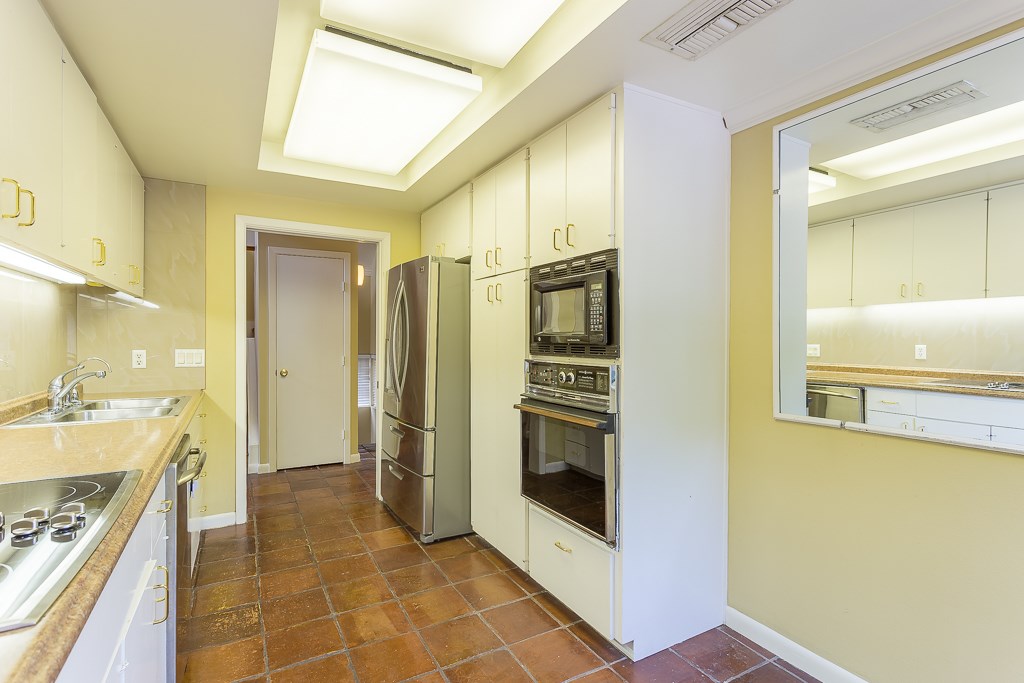 2349 Albans Road, Unit 2 Houston, TX 77005 - Photo 14 of 25 Kitchen features a sleek design with stainless steel appliances, ample cabinetry, and warm tile flooring. The lighting is bright, and there's a built-in oven and microwave. The layout is practical, offering plenty of counter space.