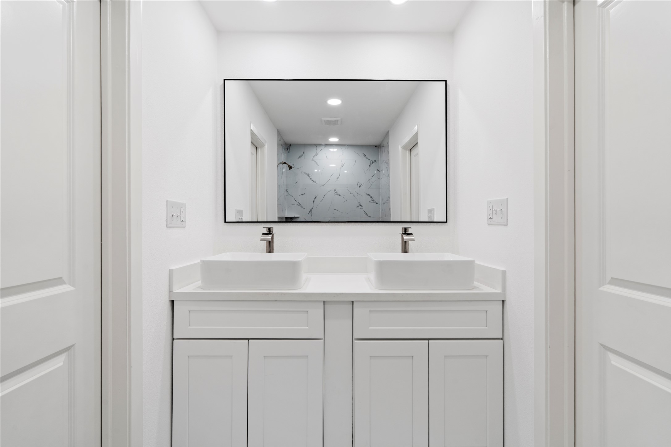 5023 Redstart Street Houston, TX 77035 - Photo 29 of 34 This modern bathroom features a clean white double vanity with contemporary vessel sinks and a large black-framed mirror that anchors the space.