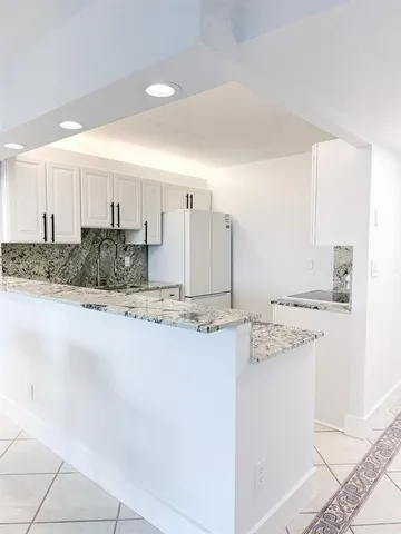 a kitchen with granite countertop sink stove and refrigerator
