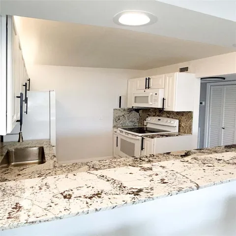 a kitchen with kitchen island white cabinets and white appliances
