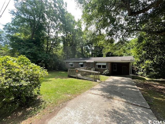 41 Harmon Street Hemingway, SC 29554 - Photo 2 of 20 Single story home with a front lawn, driveway, a carport, a wooden deck, and view of wooded area