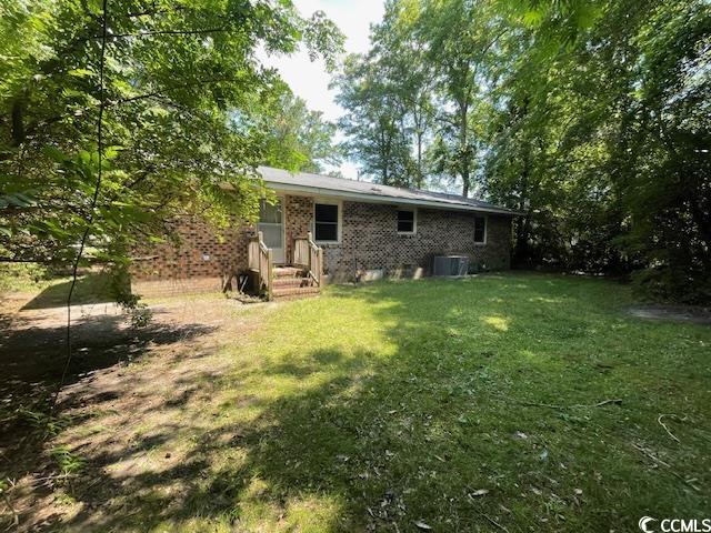 41 Harmon Street Hemingway, SC 29554 - Photo 7 of 20 Back of house featuring a lawn, central air condition unit, and brick siding