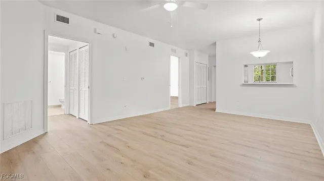 a view of an empty room with window and wooden floor