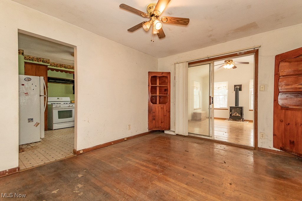 3303 River Road Perry, OH 44081 - Photo 12 of 34 Unfurnished room with hardwood / wood-style floors, ceiling fan, and a wood stove