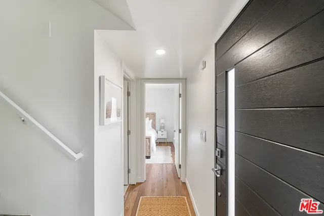a view of a hallway with wooden floor and a bathroom