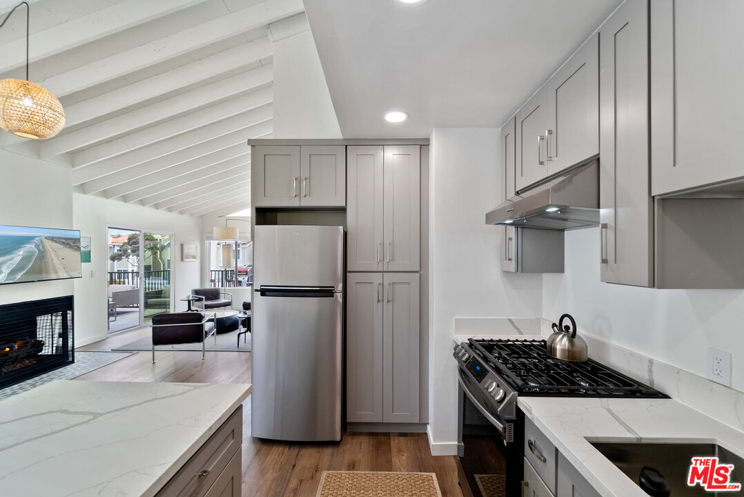 213 17th Street, Unit A Huntington Beach, CA 92648 - Photo 26 of 31 a kitchen with a refrigerator a stove cabinets and a dining table