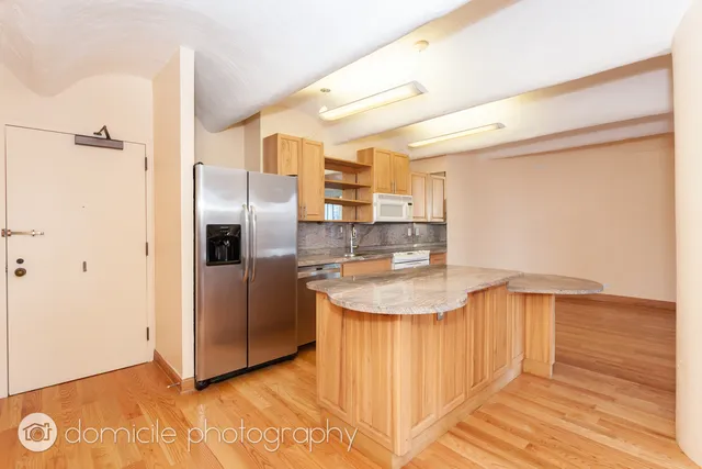 a kitchen with stainless steel appliances granite countertop a sink and a refrigerator