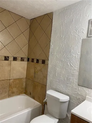 a white toilet sitting next to a bath tub and a shower