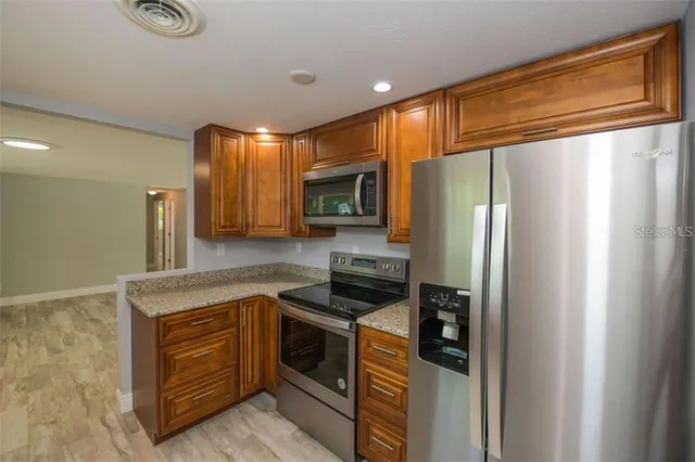 a kitchen with stainless steel appliances granite countertop a refrigerator a stove and a sink with cabinets